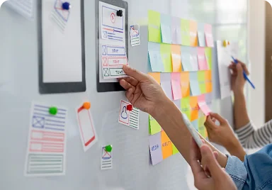 A woman gestures towards a whiteboard filled with sticky notes, showcasing ideas for a brand microsite design.